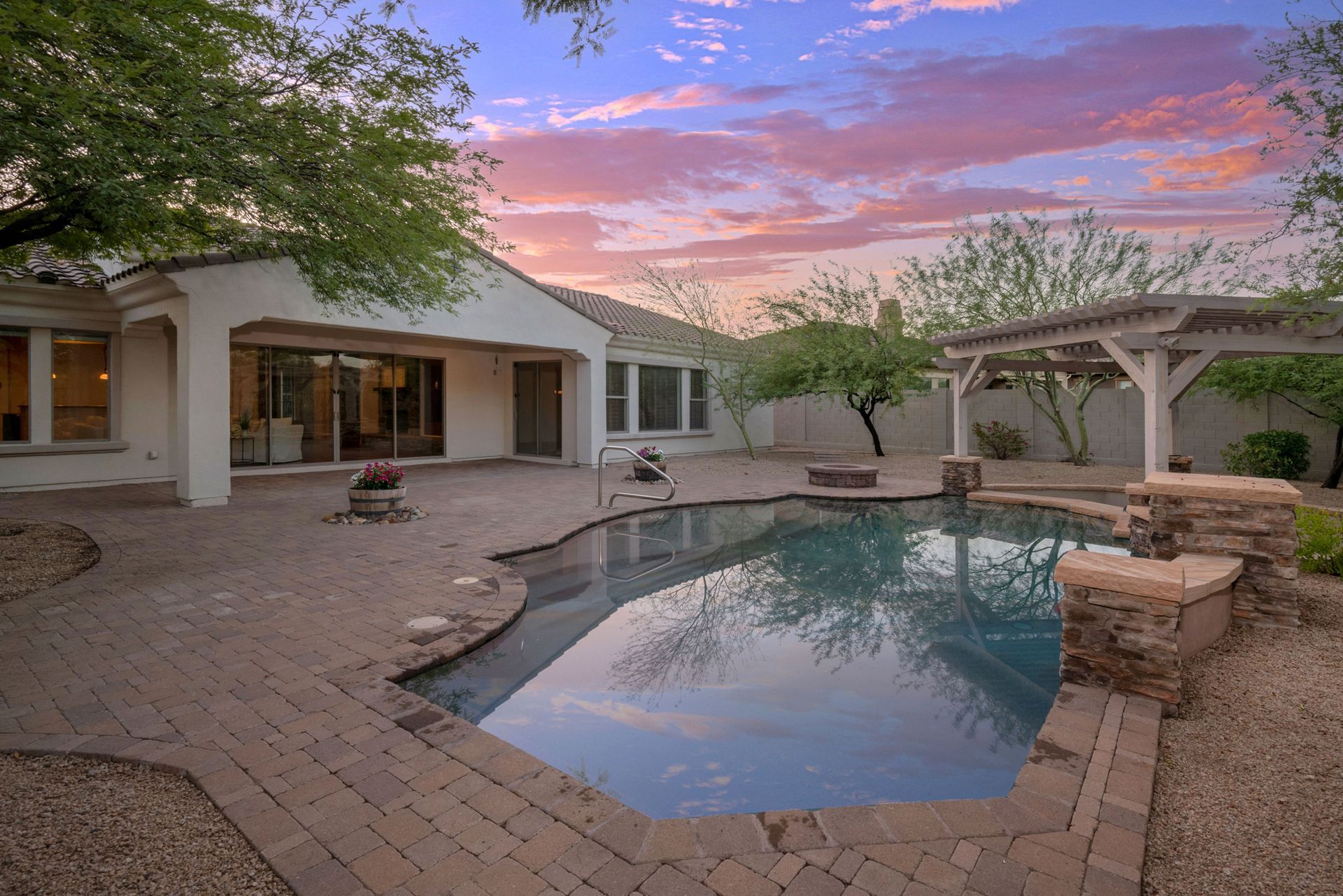A large swimming pool is in the backyard of a house.