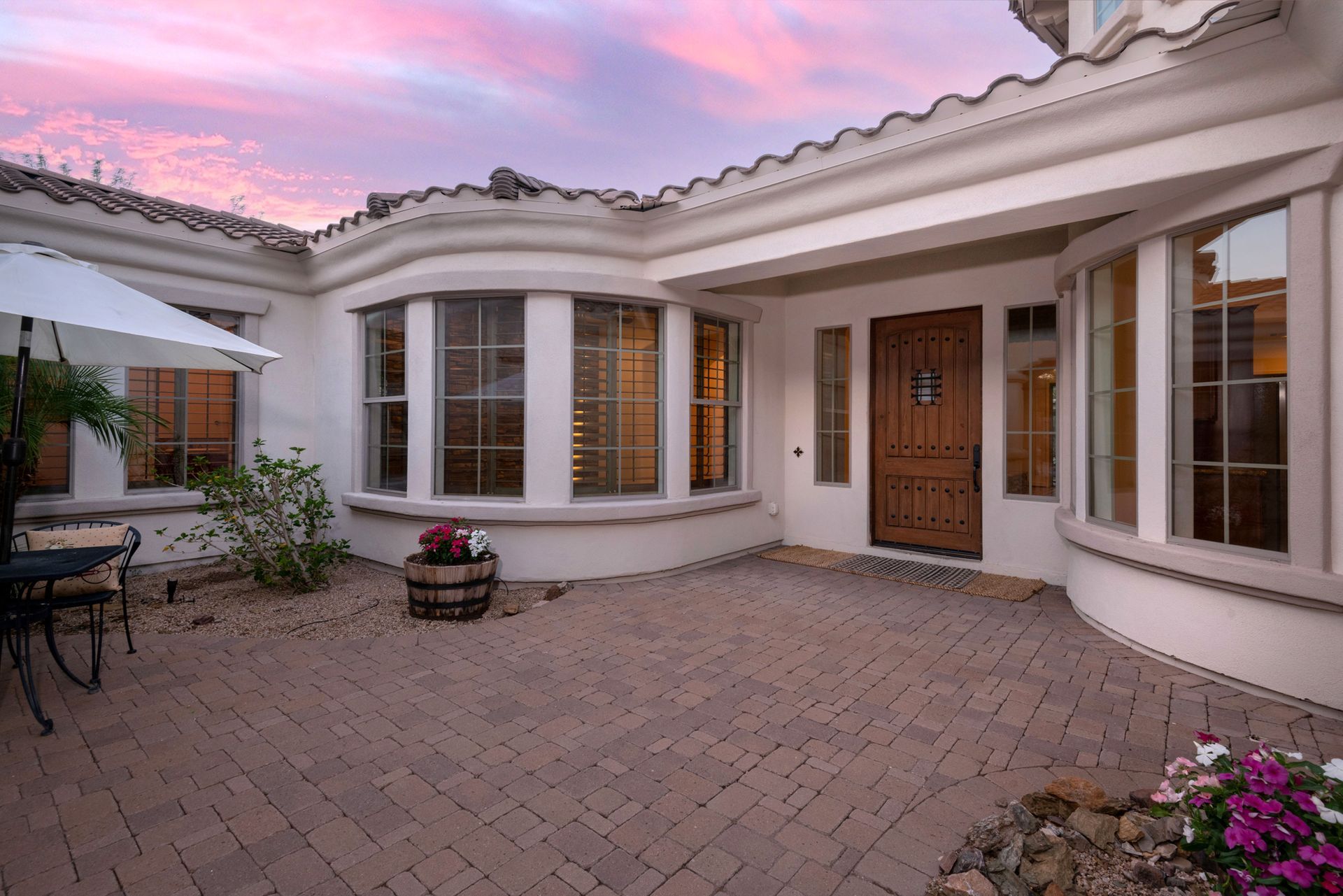 A large white house with a brick patio in front of it.