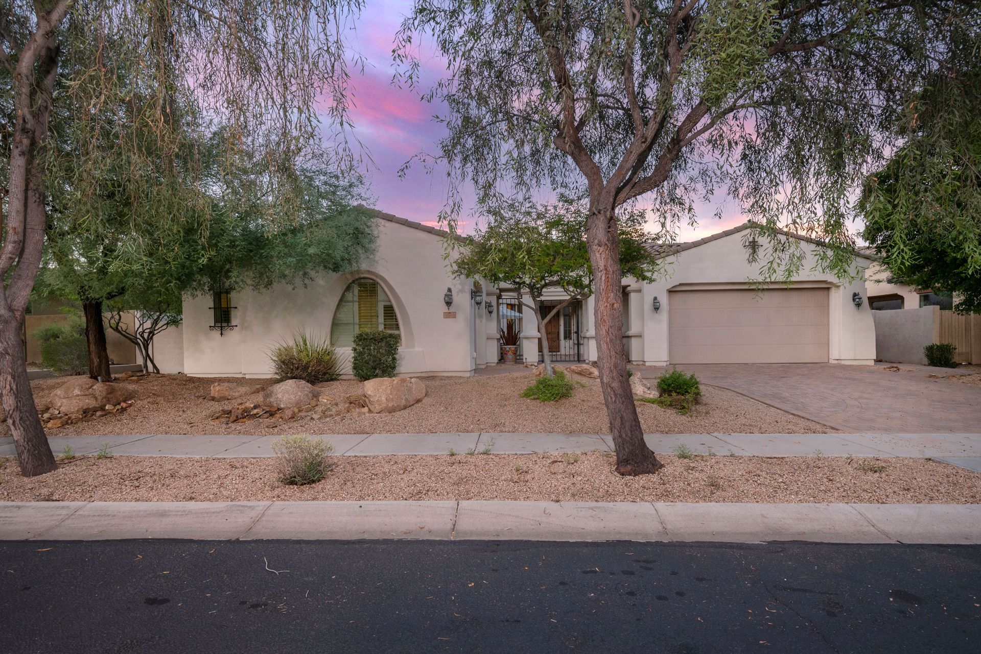 A white house with a garage and trees in front of it