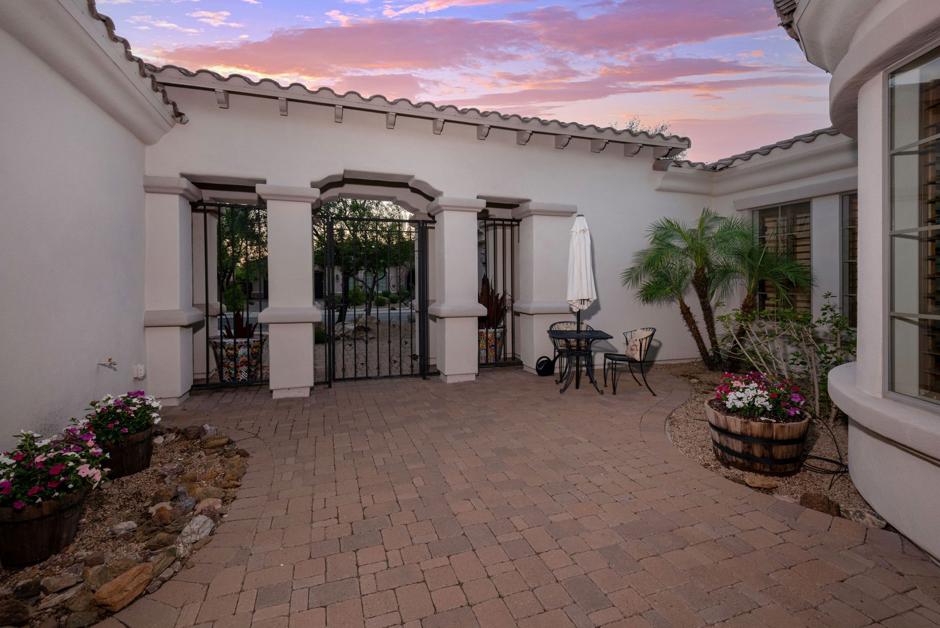 A patio with a table and chairs and a sunset in the background