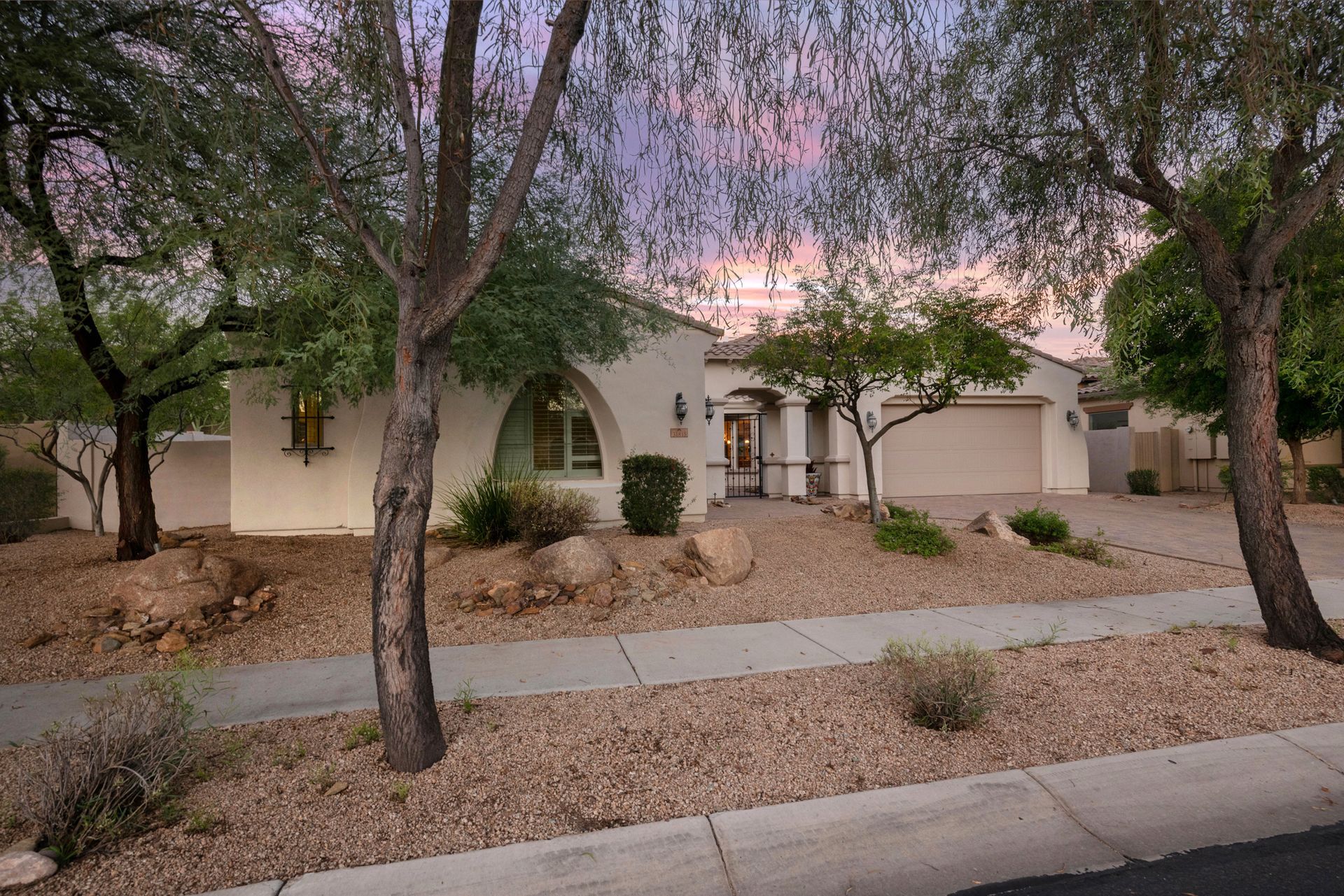 A white house with a driveway and trees in front of it