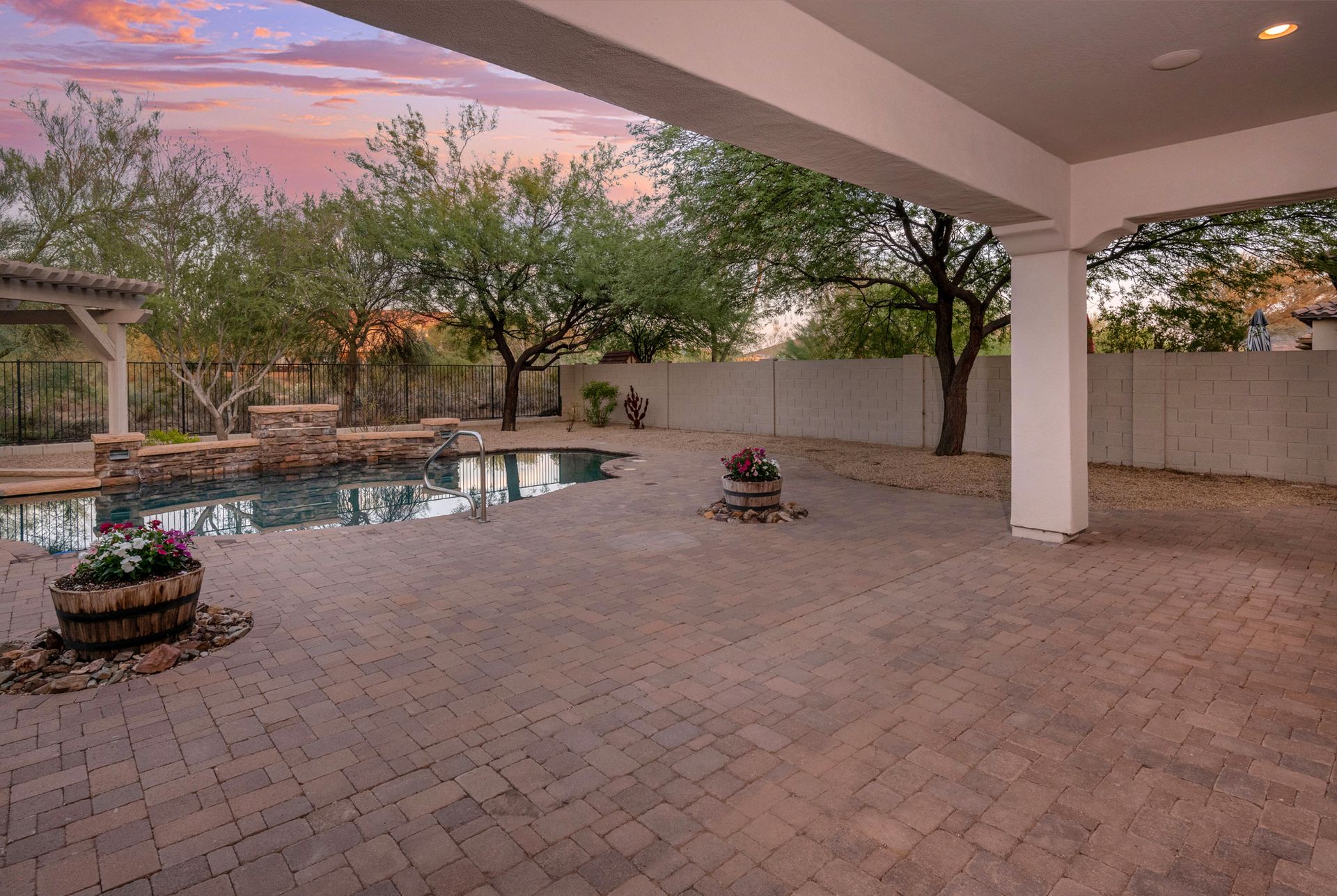 A patio with a swimming pool and trees in the background