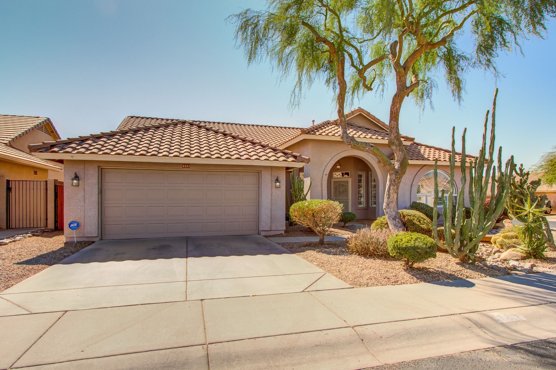 A house with a garage and a cactus in front of it.