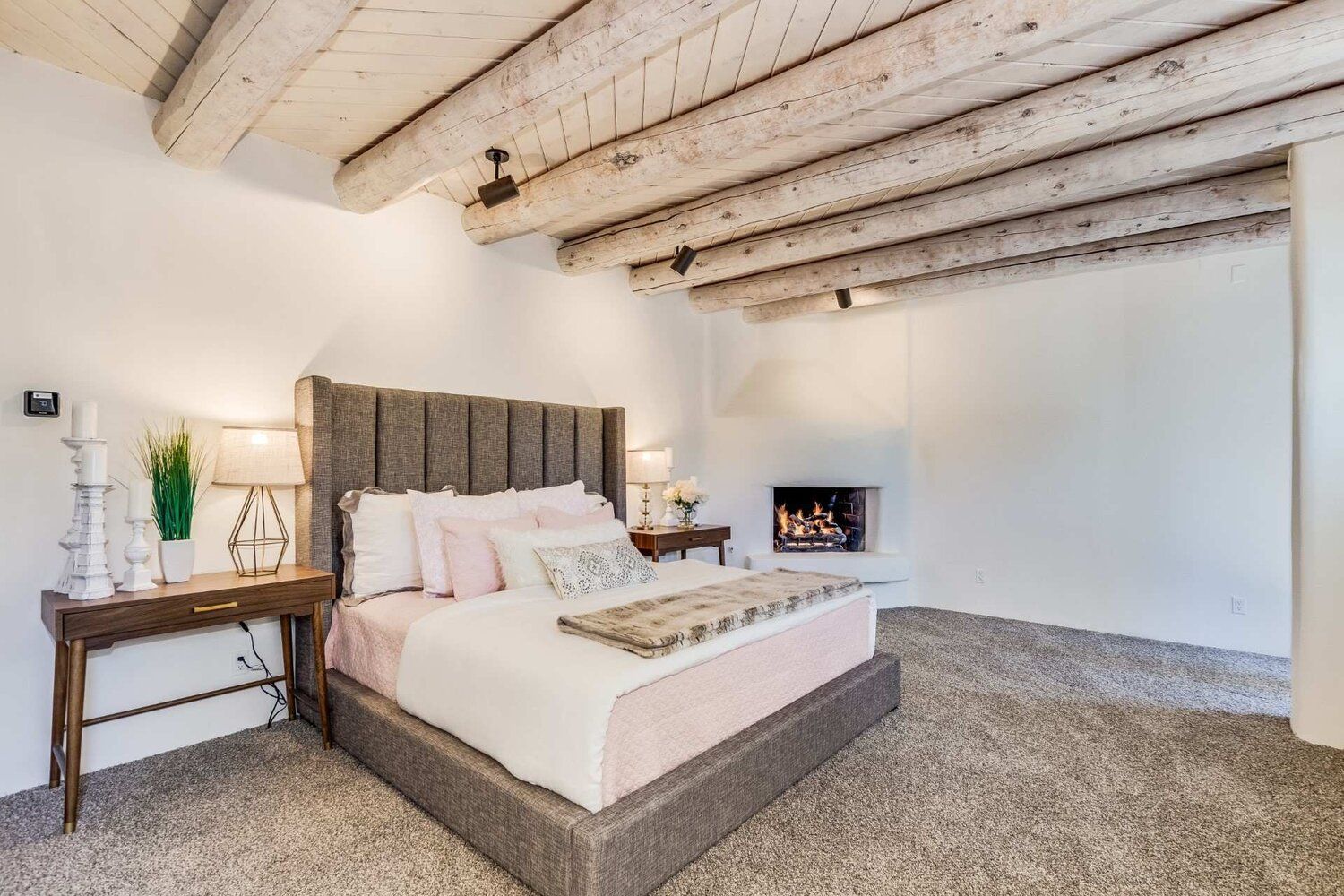 A bedroom with a large bed and a fireplace.