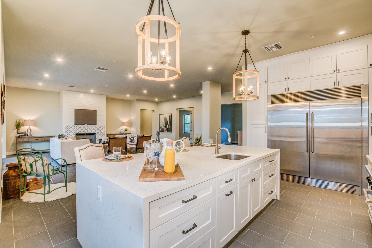 A kitchen with white cabinets and stainless steel appliances and a large island in the middle.