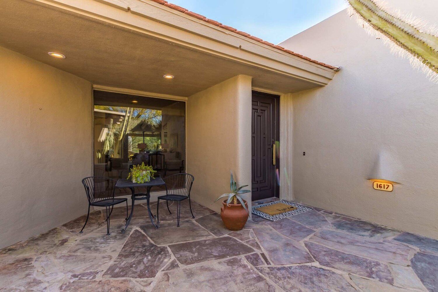 A stone patio with a table and chairs in front of a house.