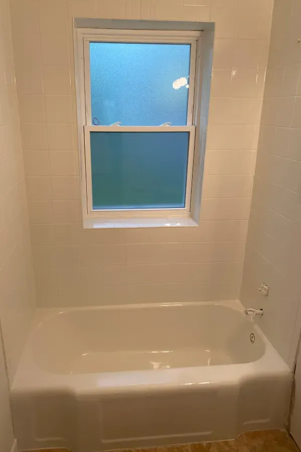 A white bathtub in a bathroom next to a window.