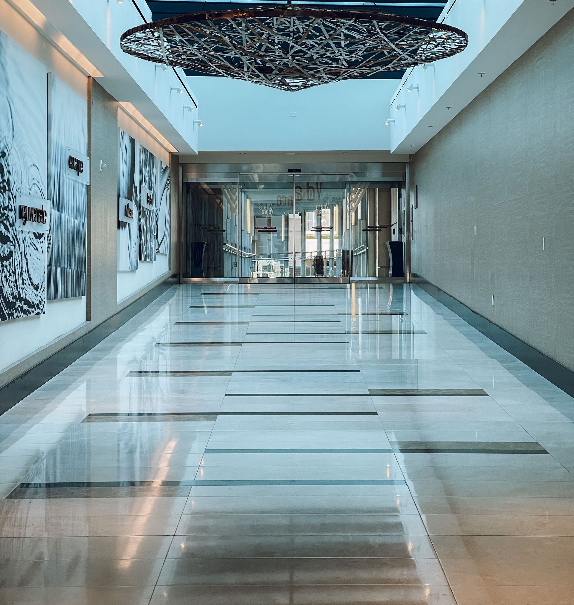 Modern hallway with polished floor, wall art, and a decorative ceiling light panel