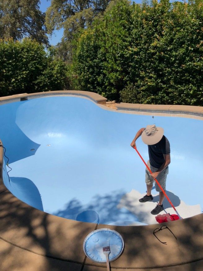 A Man is Cleaning a Pool With a Broom — Fannie Bay Pool Shop in Cullen Bay, NT