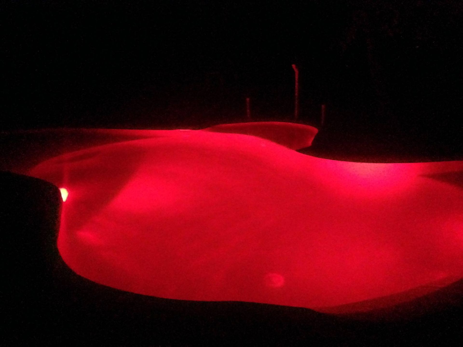 A Large Swimming Pool is Lit Up With Red Lights at Night — Fannie Bay Pool Shop in Winnellie, NT