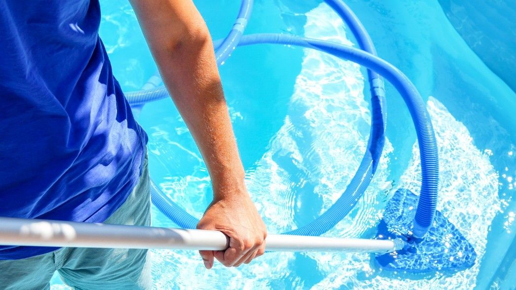 A Man is Cleaning a Swimming Pool With a Cleaner — Fannie Bay Pool Shop in Larrakeyah, NT