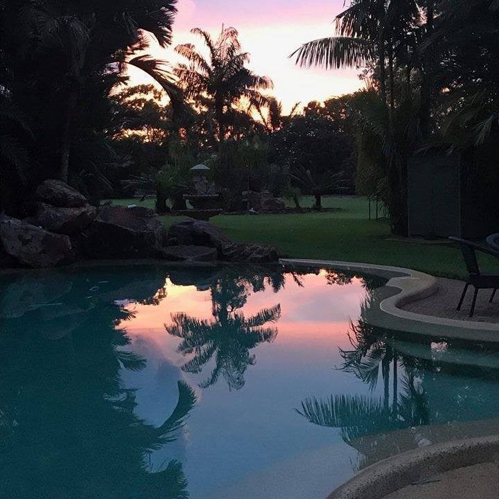 A Sunset Over a Swimming Pool With Palm Trees — Fannie Bay Pool Shop in Winnellie, NT