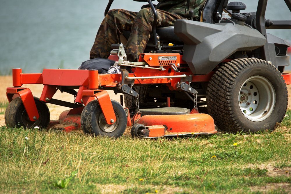 A man is riding a lawn mower on top of a lush green field.