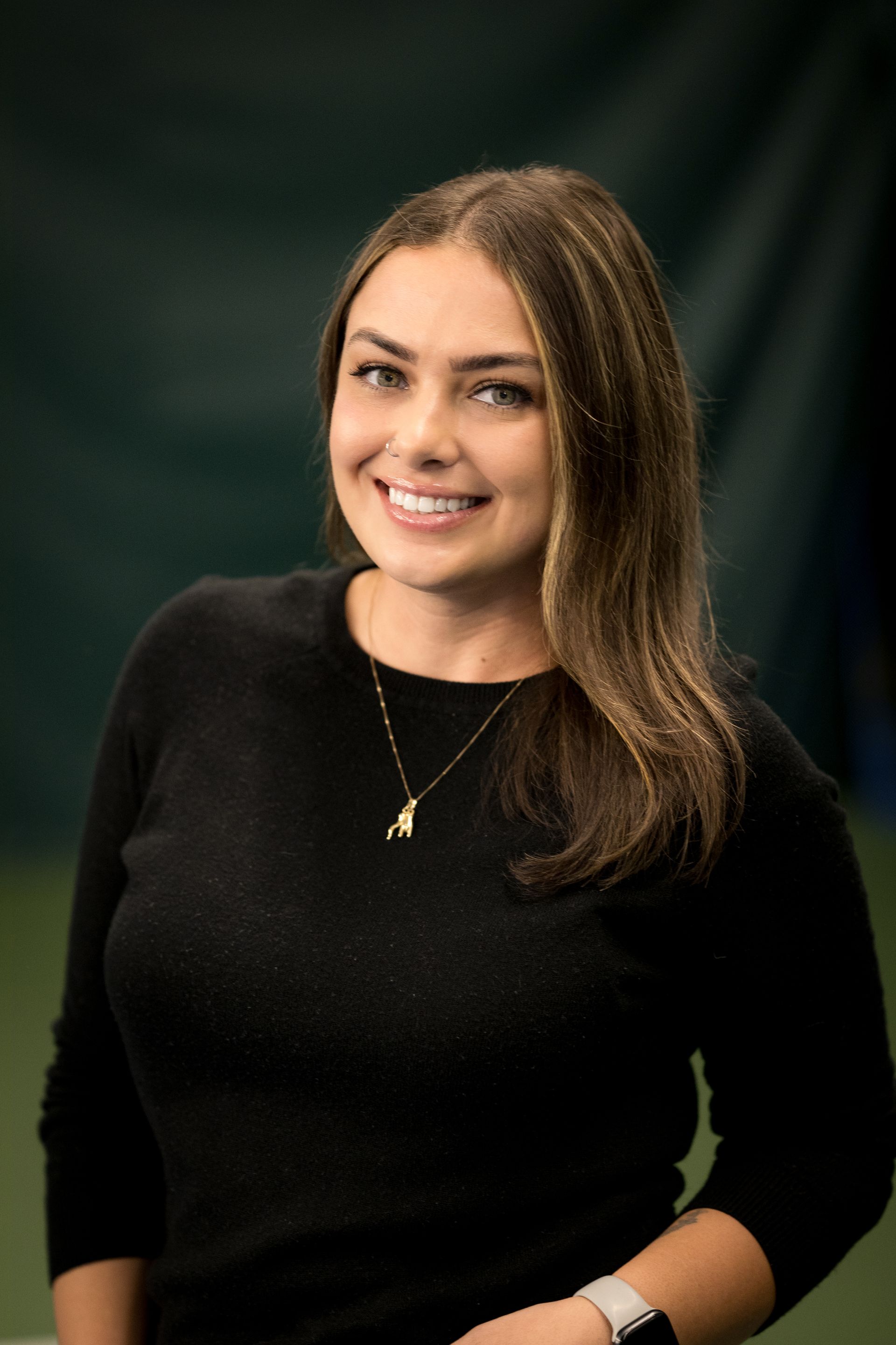 A woman with long brown hair is smiling for the camera.