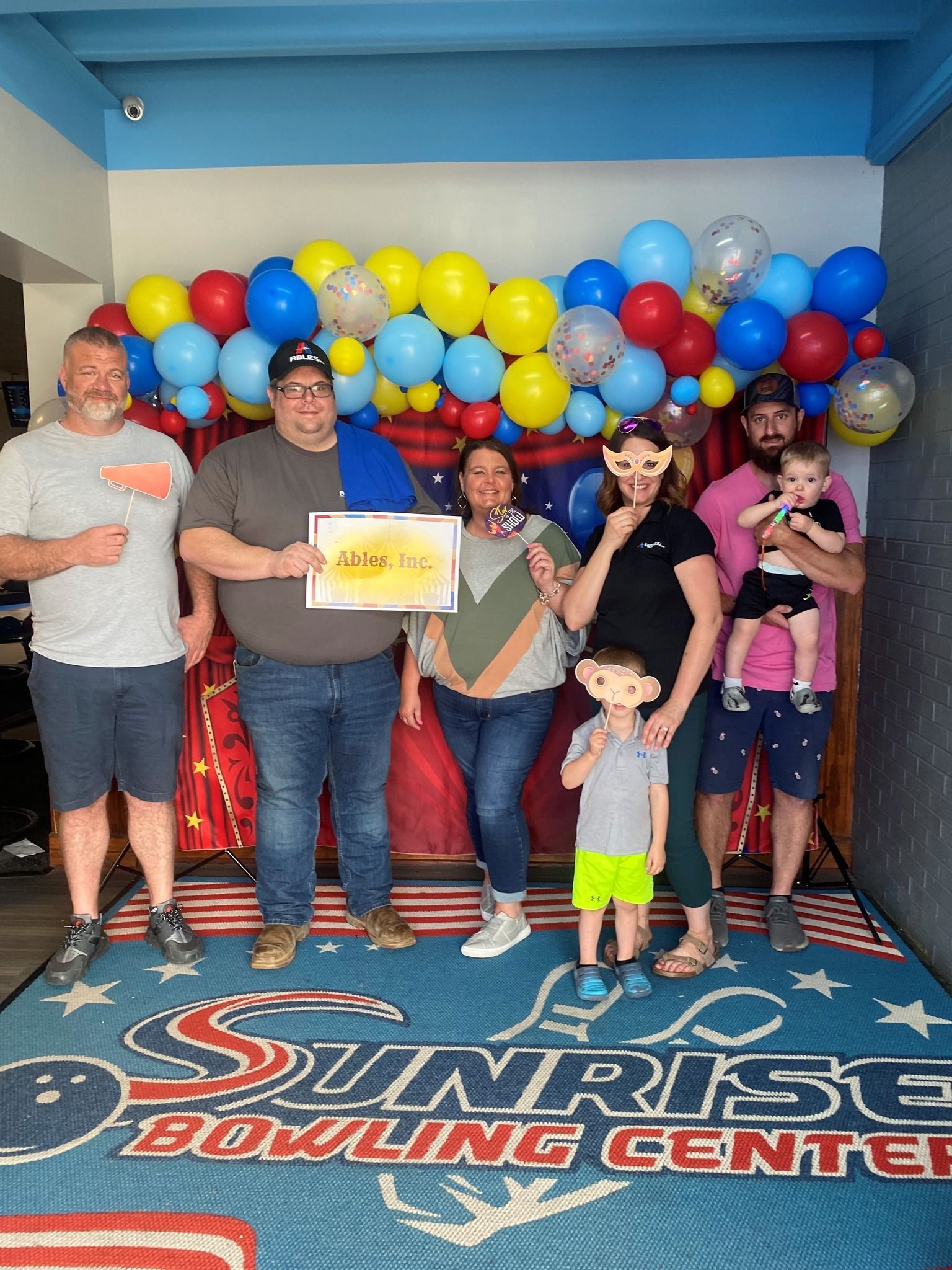 A group of people standing next to each other in a room with balloons.