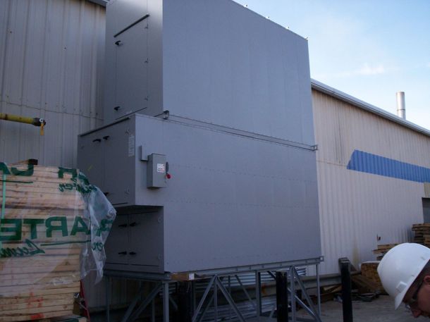 A man wearing a hard hat is standing in front of a large gray box that says ' ataa ' on it