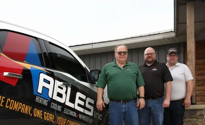Three men are standing in front of a van that says ables