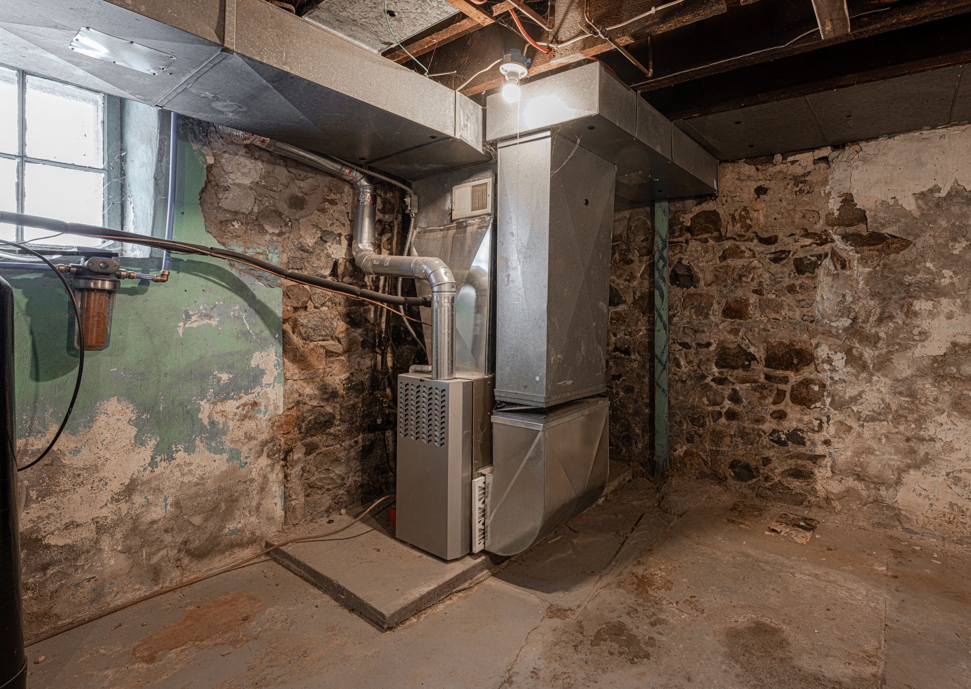 A basement with a furnace and a brick wall.