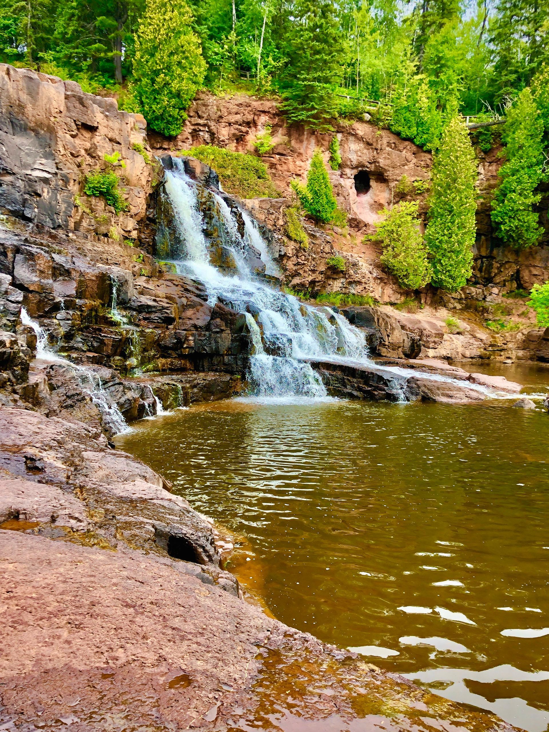 A waterfall is surrounded by trees and rocks in the middle of a forest.