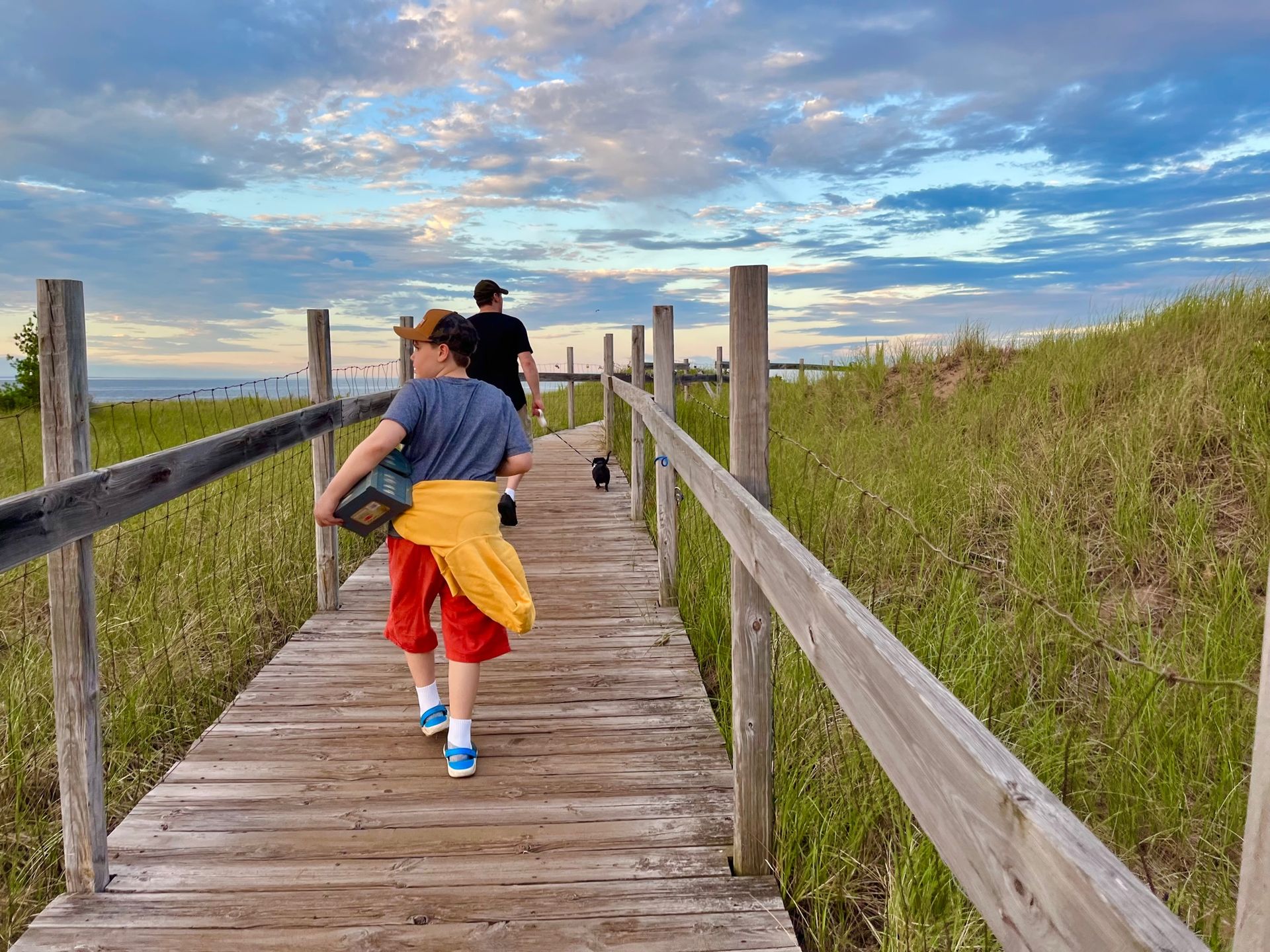 A couple of people are walking down a wooden walkway.
