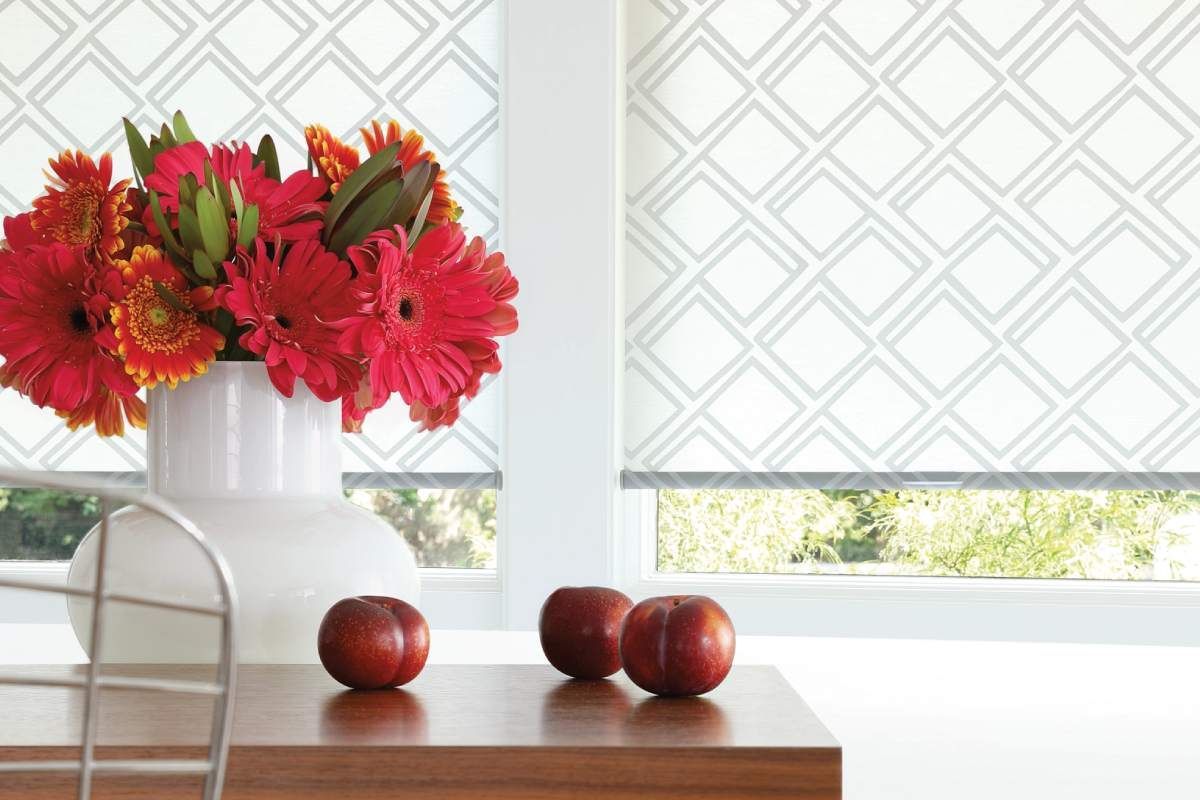 Hunter Douglas Designer Roller Shades with a vase of red flowers and fruits.
