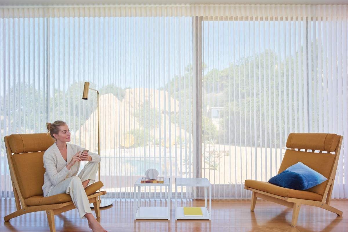 A young woman sitting in front of Hunter Douglas Luminette® Sheer Panels.