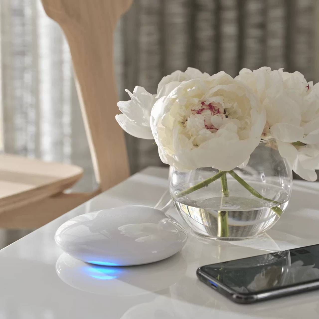 Hunter Douglas PowerView® Hub on a Table Next to a Phone and Flowers
