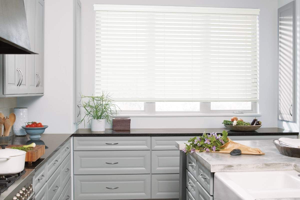Lightly-colored Hunter Douglas EverWood® Faux Wood Blinds above a white kitchen sink.