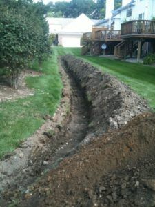 A large pile of dirt is in the middle of a yard next to a house.