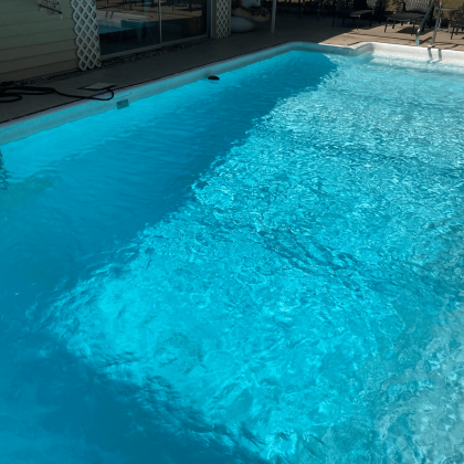 A large swimming pool filled with blue water in a backyard.