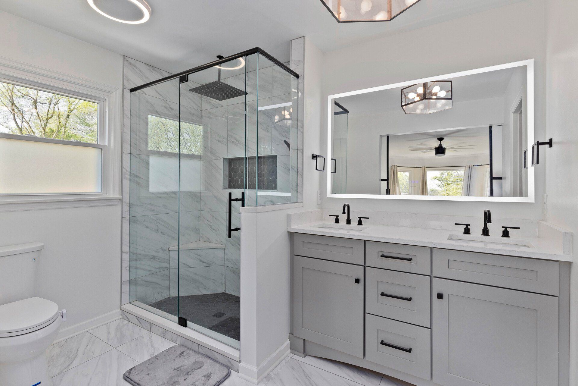 A bathroom with two sinks , a toilet , and a walk in shower.