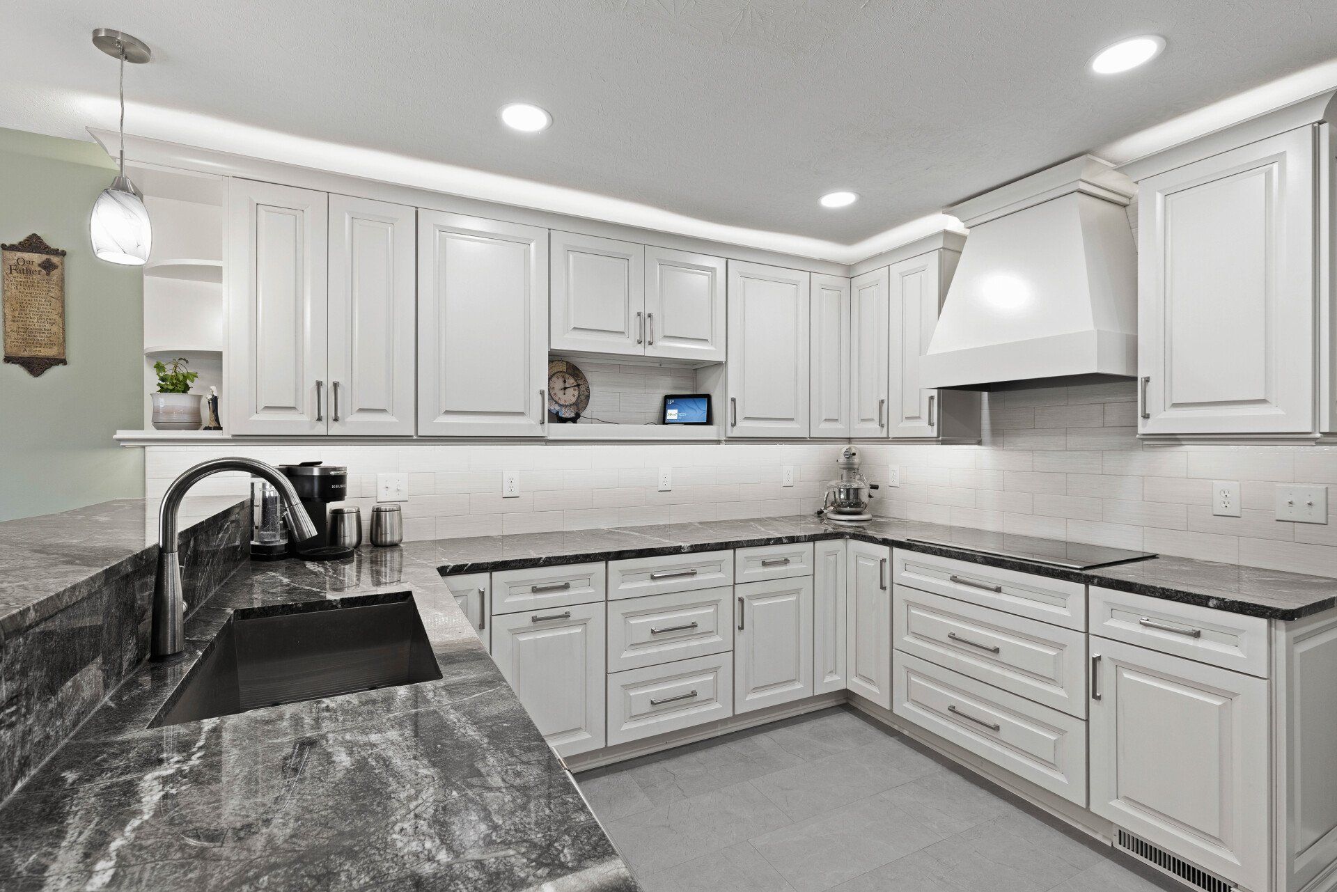 A kitchen with white cabinets , granite counter tops , and a sink.