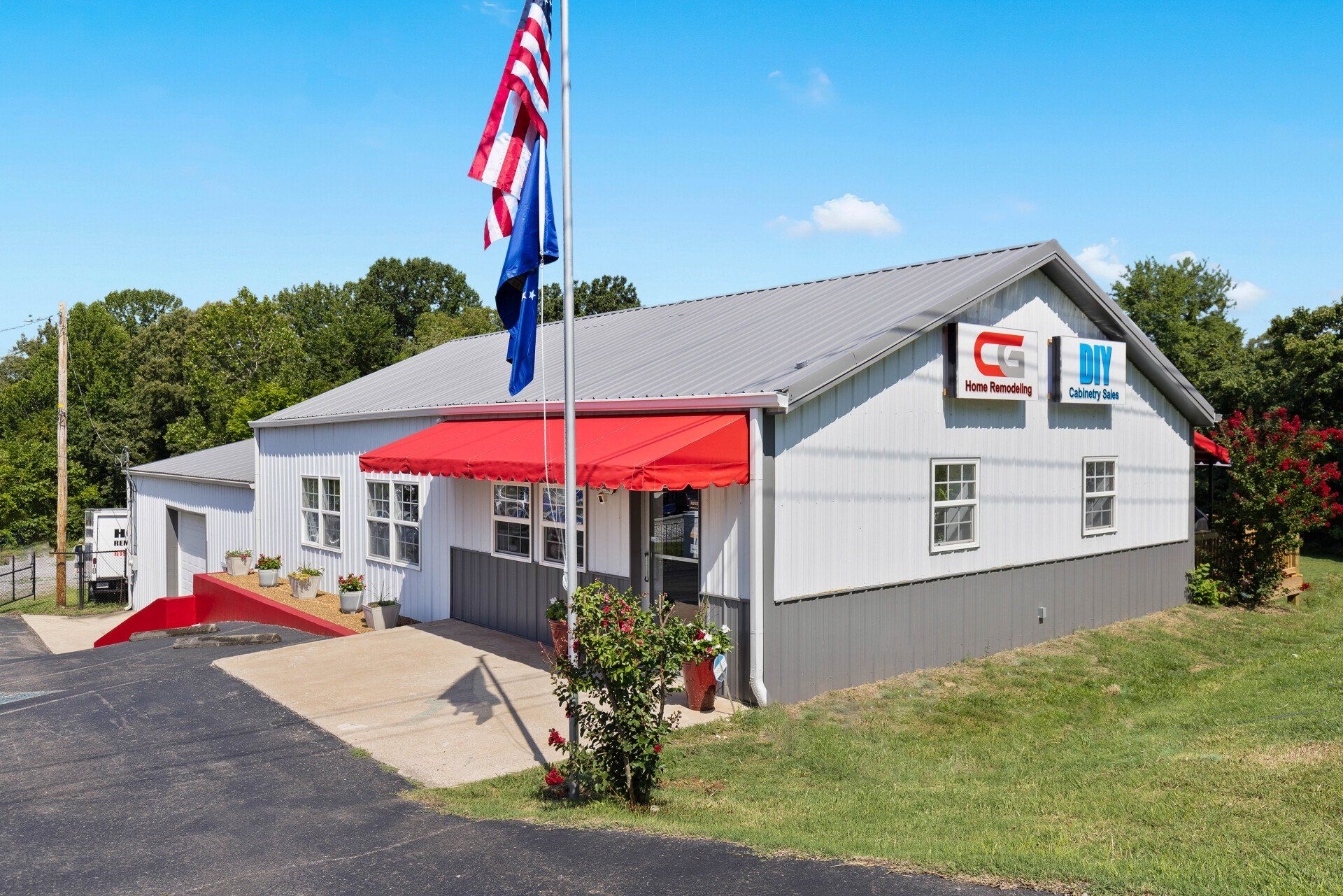 A white building with a red awning and an american flag