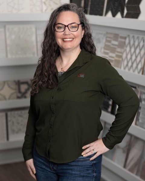 A woman wearing glasses and a green shirt is standing with her hands on her hips.