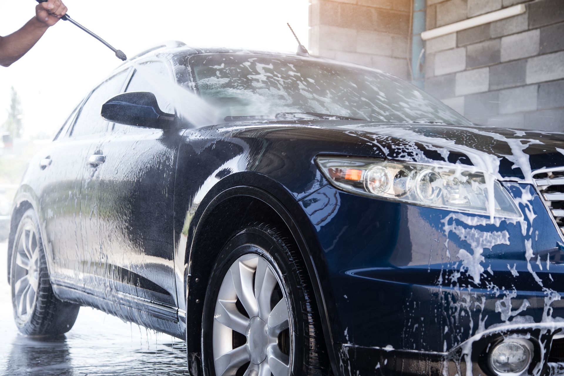 A person is washing a car with a high pressure washer.