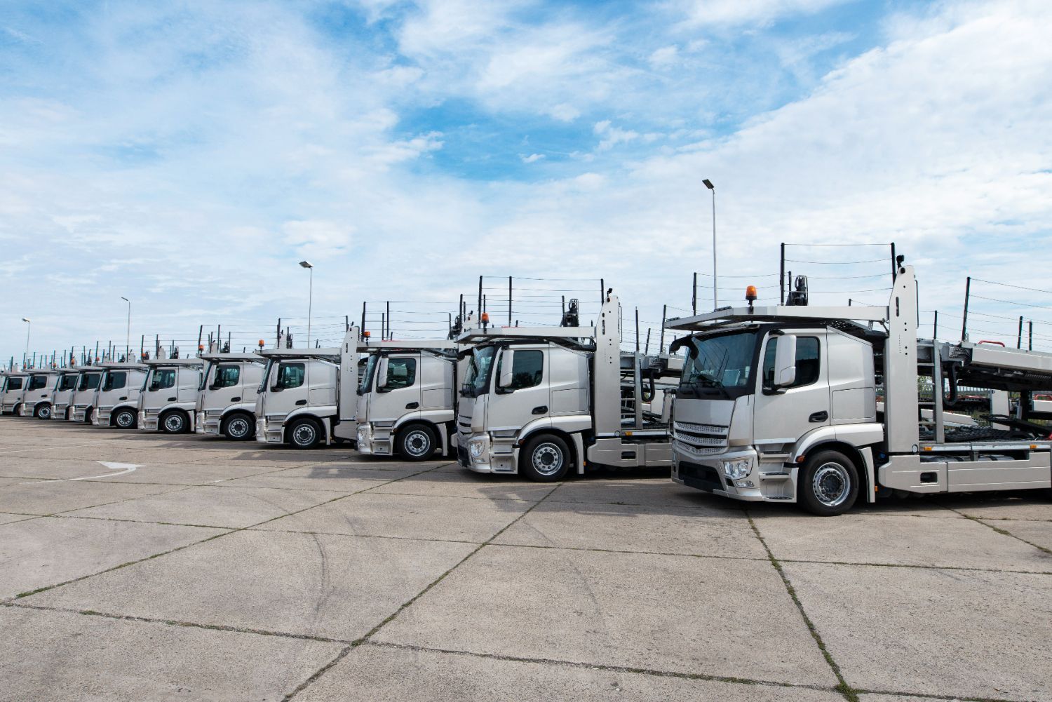 A row of white trucks are parked in a parking lot.