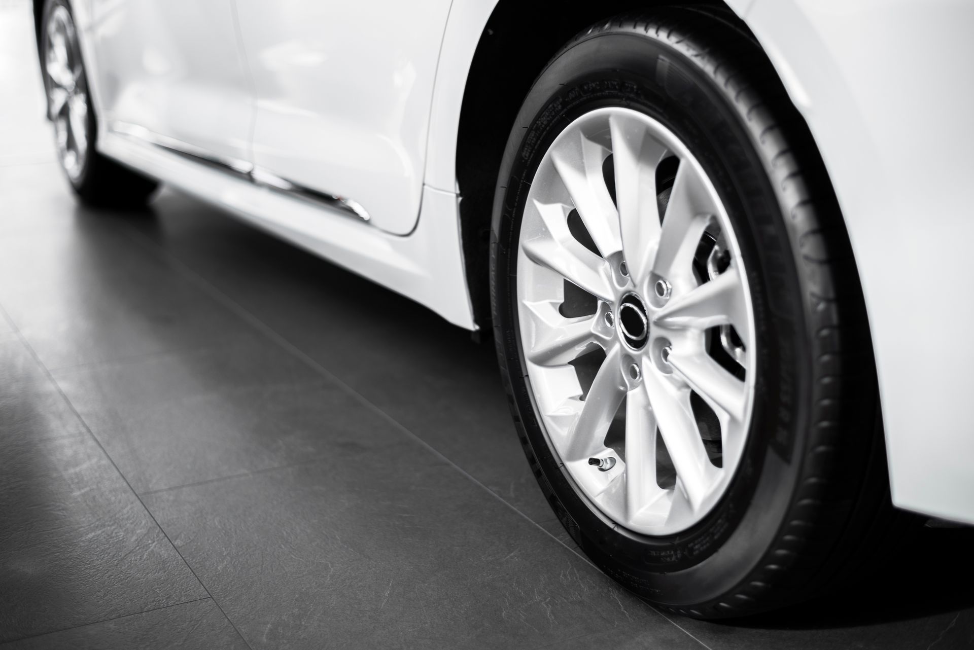 A close up of a white car 's tire in a showroom.