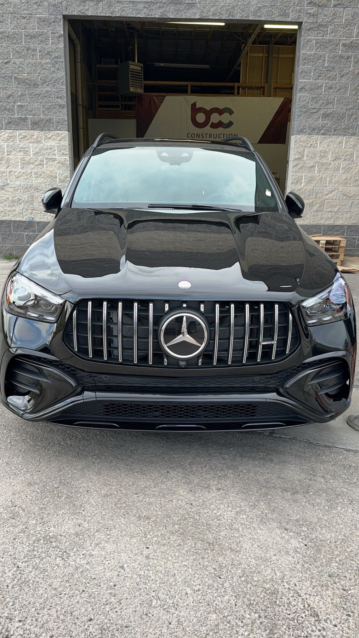 A black mercedes benz is parked in front of a building.