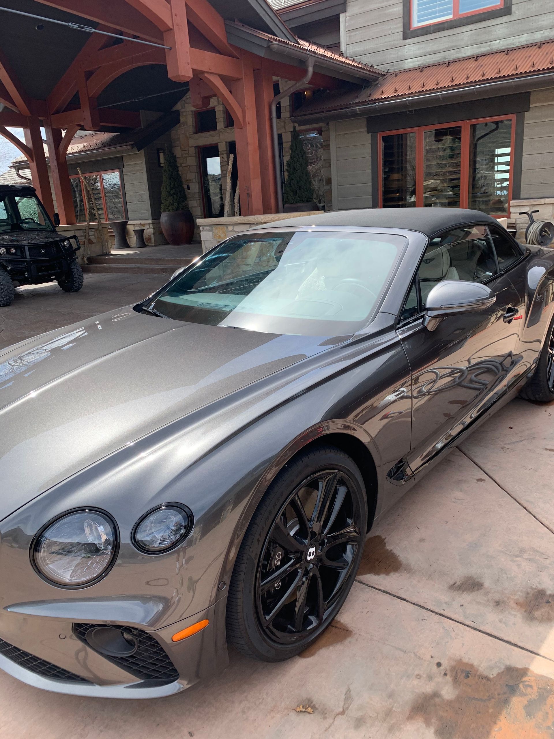 A bentley convertible is parked in front of a house.