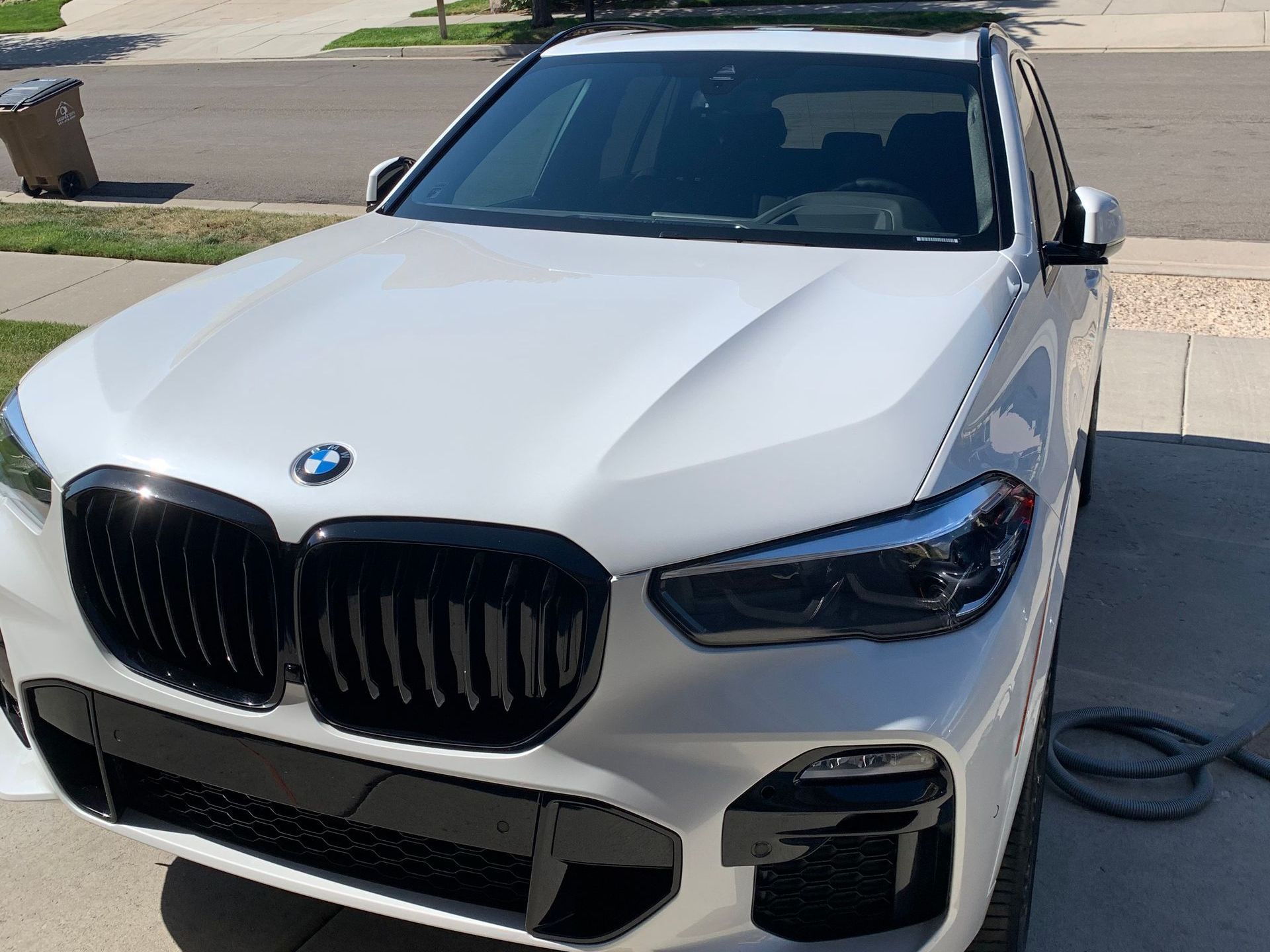 A white bmw is parked in front of a house