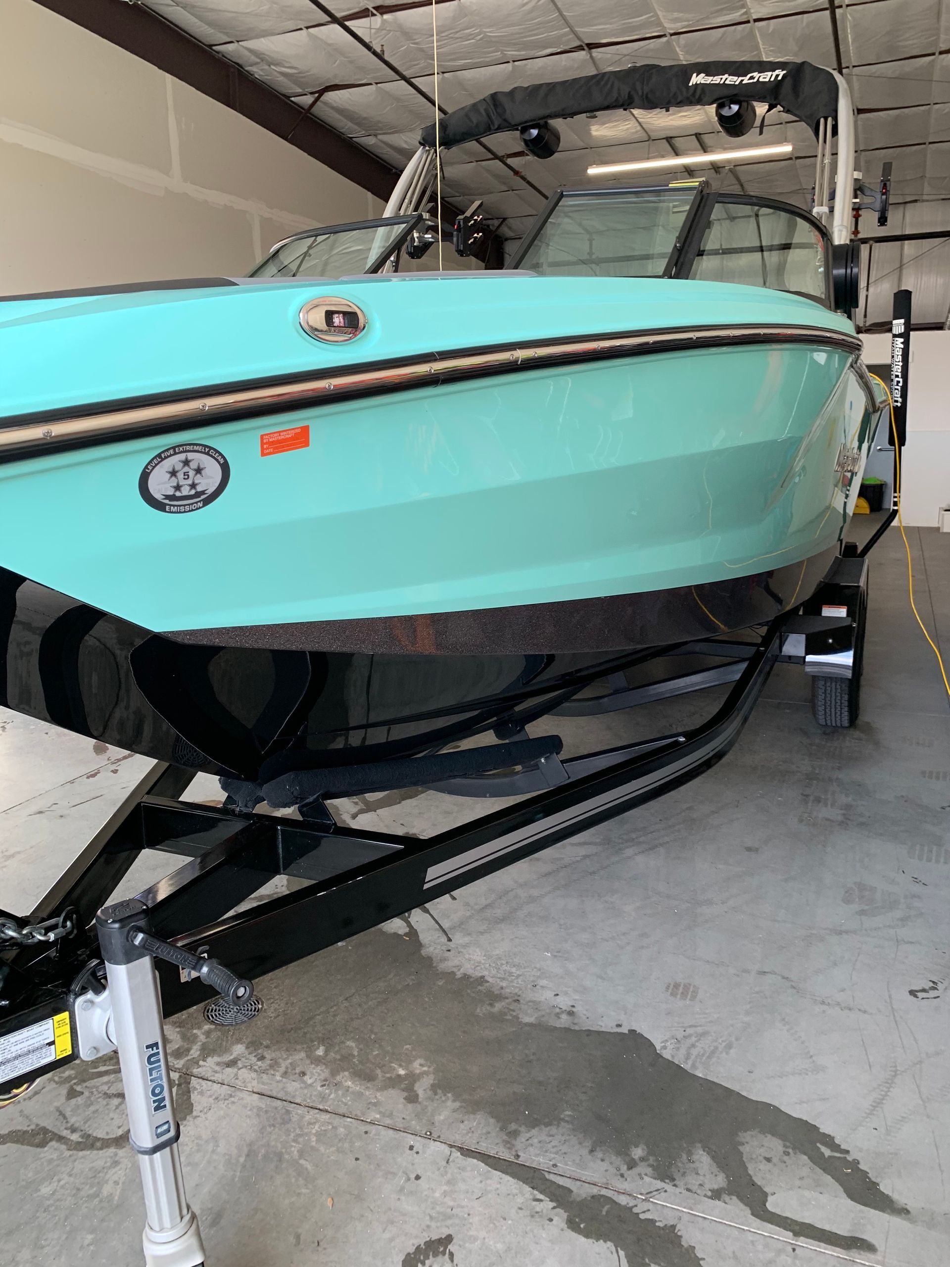 A blue boat is parked in a garage on a trailer