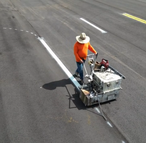 Worker using line striping machine painting white lines in Rio Rancho New Mexico parking lot