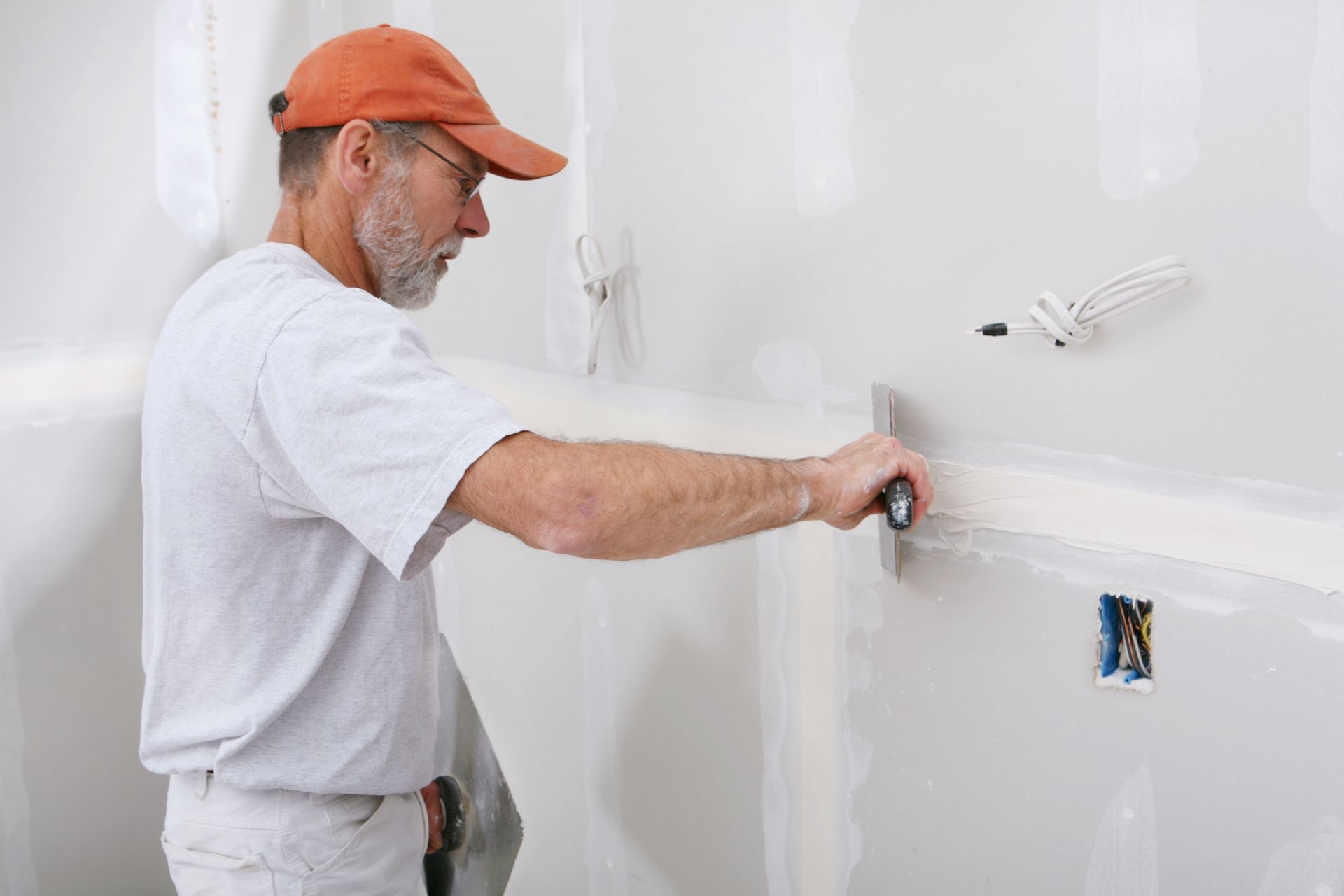 A man is plastering a wall with a spatula.