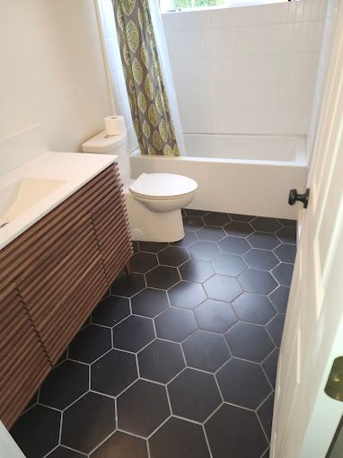 A man is kneeling on the floor fixing a cabinet in a kitchen.