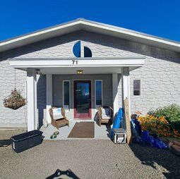 A house with a porch and chairs in front of it.