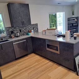 A kitchen with stainless steel appliances and wooden floors.