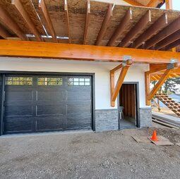 A garage door is being installed on a house under construction.