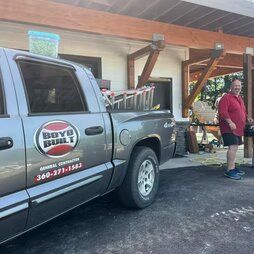 A man is standing next to a truck parked in front of a house.