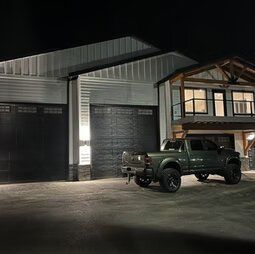 A green truck is parked in front of a house at night.