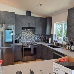 A kitchen with stainless steel appliances and gray cabinets.